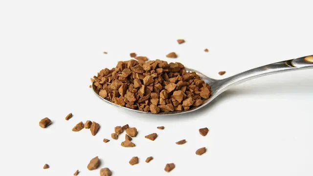 colher cheia de grãos de café solúvel liofilizado